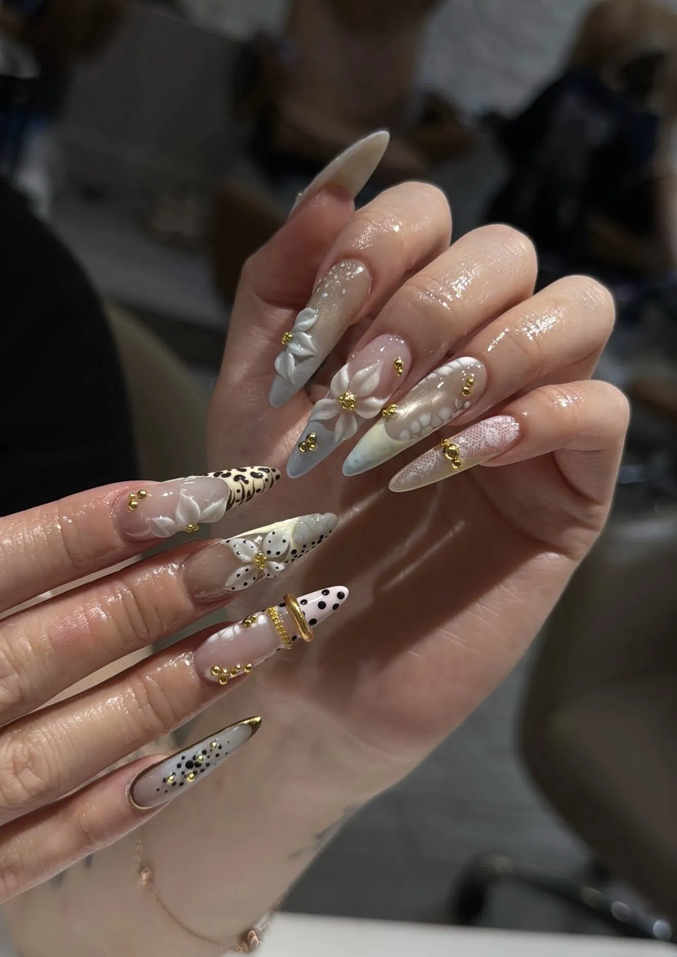 Long neutral nails with 3D white flowers, lace, leopard accents and gold beads