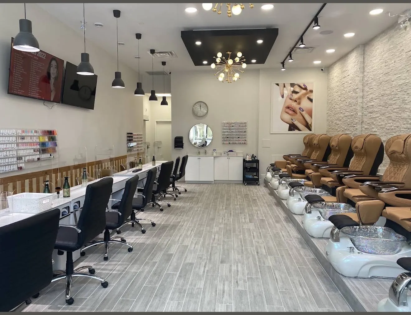 Inside Pedi N Nails Dundas East: tan pedicure chairs along a stone wall, manicure stations opposite